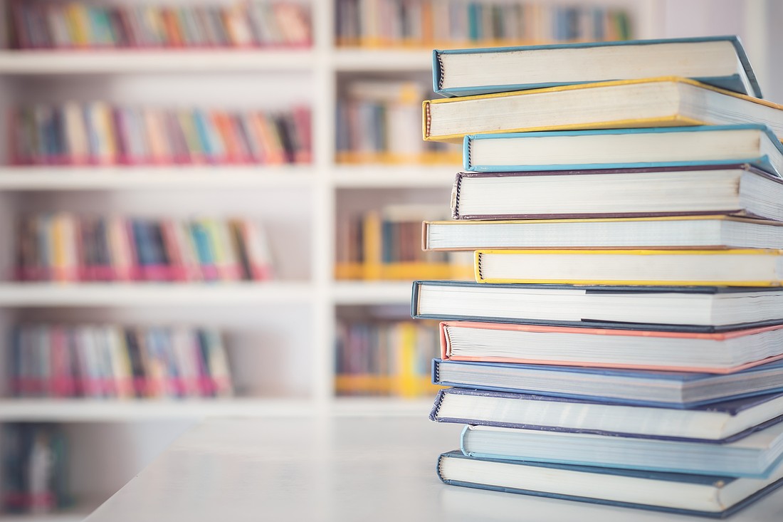 Close up book stack on the table in the library room and blurred space of bookshelf background