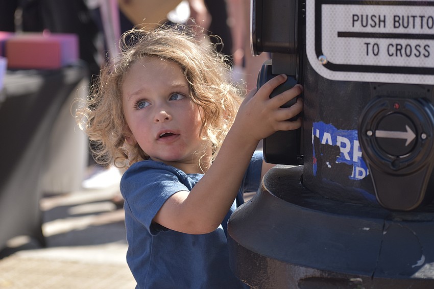 Shai Bluvol, 2, presses the button for the crosswalk as he prepares to cross with a parent.
