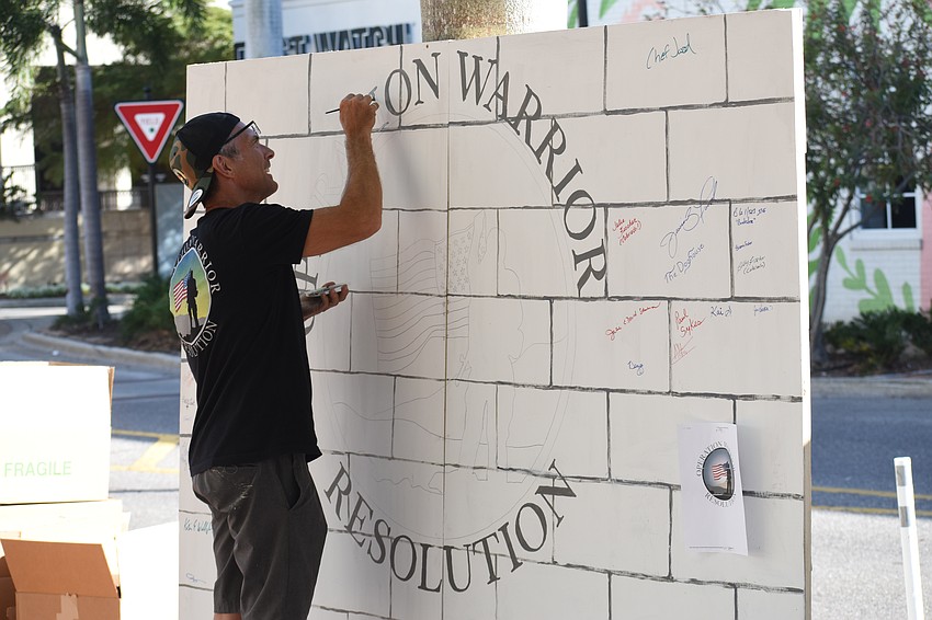 Daytona Beach veteran Daniel Jack paints a community board featuring signatures in support of Operation Warrior Resolution.
