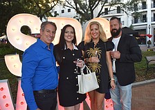 Mike and Julie Paige, and Amber and Lenny Larson, pose by an "SRQ Wine" sign.