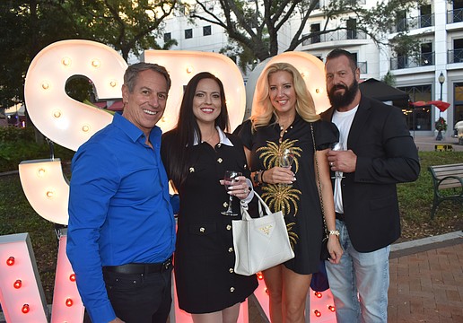 Mike and Julie Paige, and Amber and Lenny Larson, pose by an "SRQ Wine" sign.