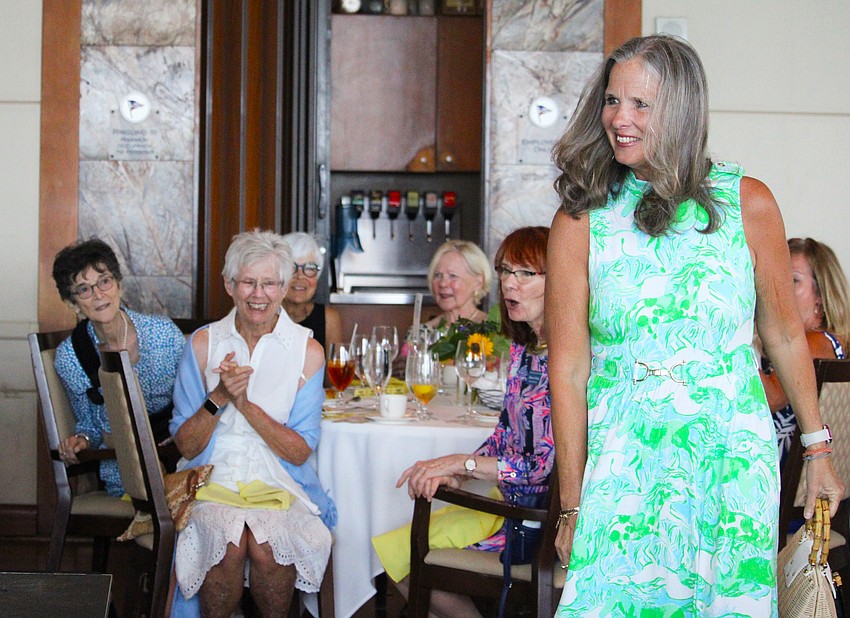 Jenny Mott-Mueller flashes a smile as Sunflower Soiree attendees look on.