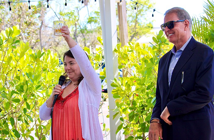 Wearing her mother's favorite color, Abby Ferreira, one of Cathy Ann "Cam" Maddox's children, raises a glass in memory of her mother on March 21 at Harry's Continental Kitchens with Brian Maddox. He said his late wife wanted a celebration of life that brought together loved ones and friends to smile, share fond memories and show their support for the Longboat Key Turtle Watch, a conservation program she passionately championed.