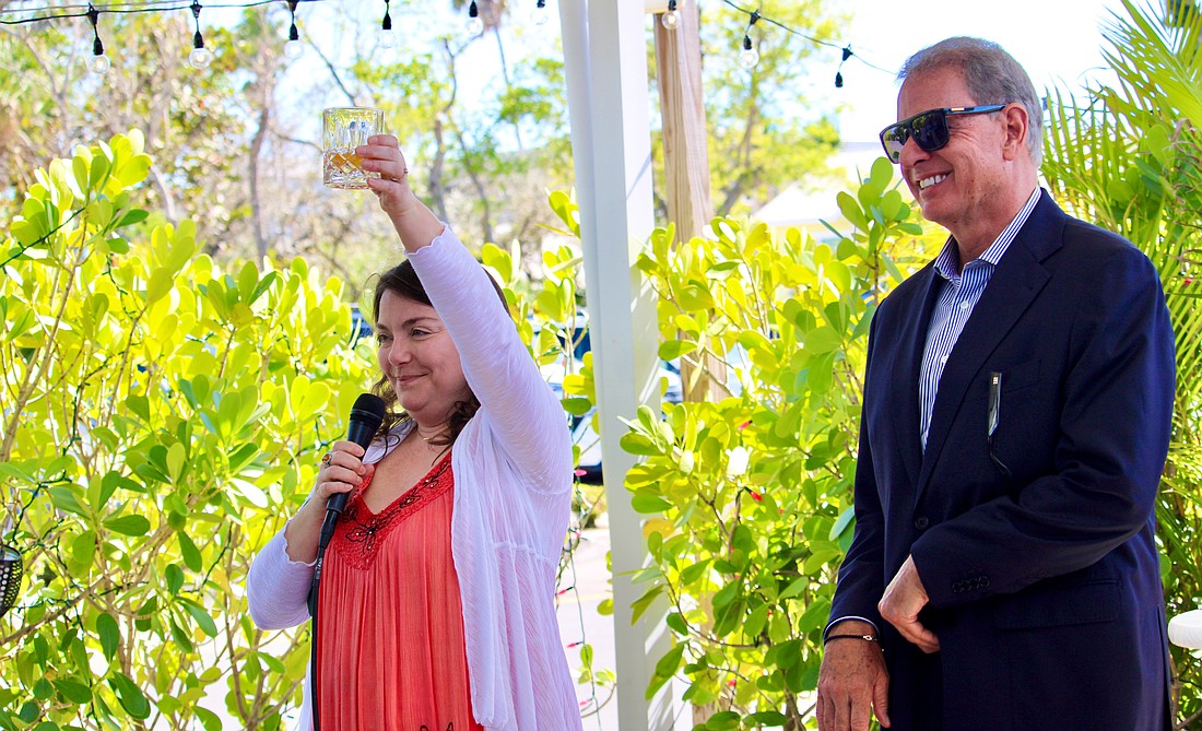 Wearing her mother's favorite color, Abby Ferreira, one of Cathy Ann "Cam" Maddox's children, raises a glass in memory of her mother on March 21 at Harry's Continental Kitchens with Brian Maddox. He said his late wife wanted a celebration of life that brought together loved ones and friends to smile, share fond memories and show their support for the Longboat Key Turtle Watch, a conservation program she passionately championed.