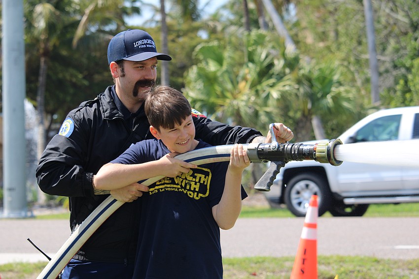 Noah Lindsay tests out firefighting equipment with the help of Ryan Corso at the Longboat Key Fire Rescue open house March 25 at Station 92. Lindsay said he hopes to one day become an engineer.