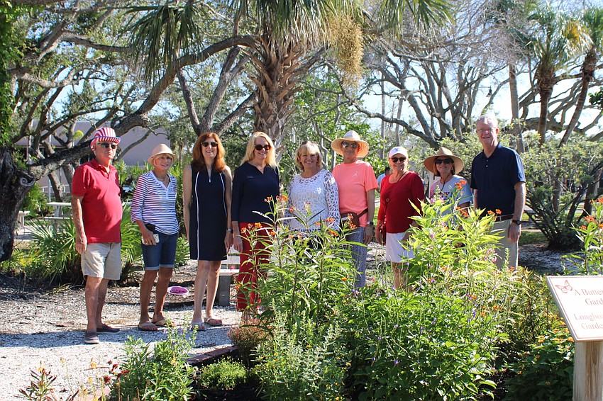 Garden Club members and volunteers stand near the butterfly garden in Bicentennial Park, a space the group has helped restore and maintain as a community gathering place.
