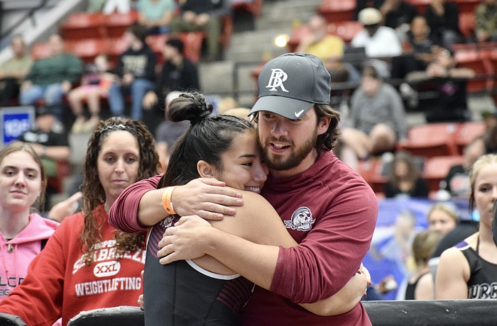 Braden River High girls weightlifting coach Jordan Borges (right) shares a hug with senior Payton Mangay-Ayam (left). Borges said he has seen multiple Florida high school coaches leave their positions because of financial strain.