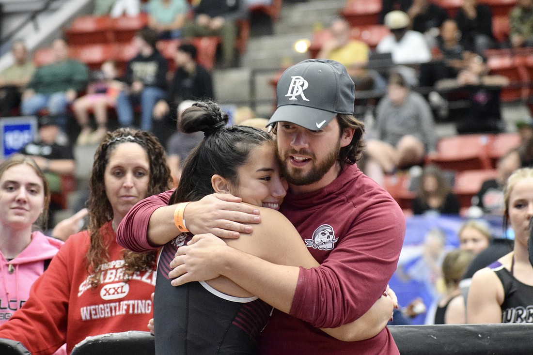 Braden River High girls weightlifting coach Jordan Borges (right) shares a hug with senior Payton Mangay-Ayam (left). Borges said he has seen multiple Florida high school coaches leave their positions because of financial strain.