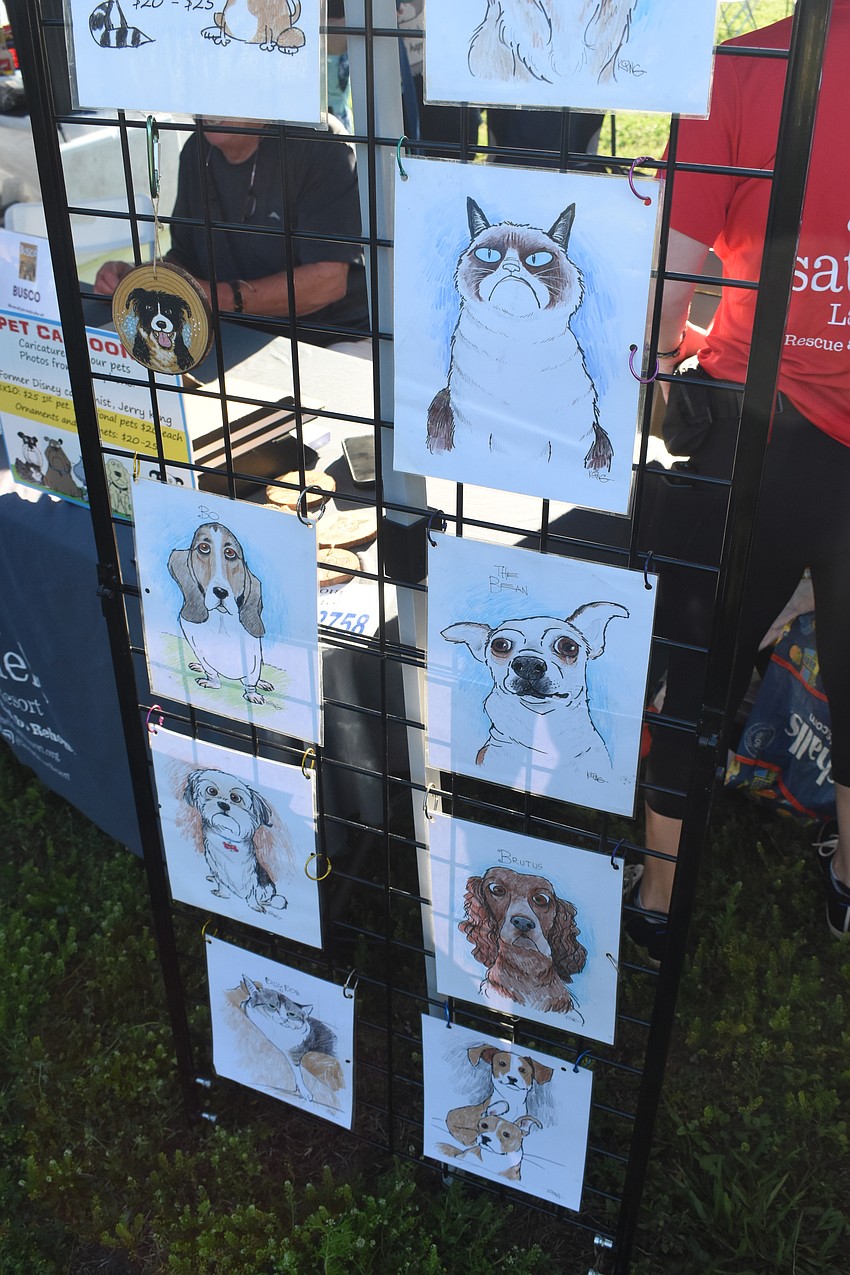 Drawings of pets by cartoonist Jerry King are displayed at the table where he is seated.