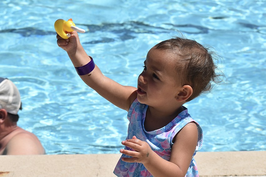 Noor Hachoum, 1, shows her prize to a lifeguard at the stand.