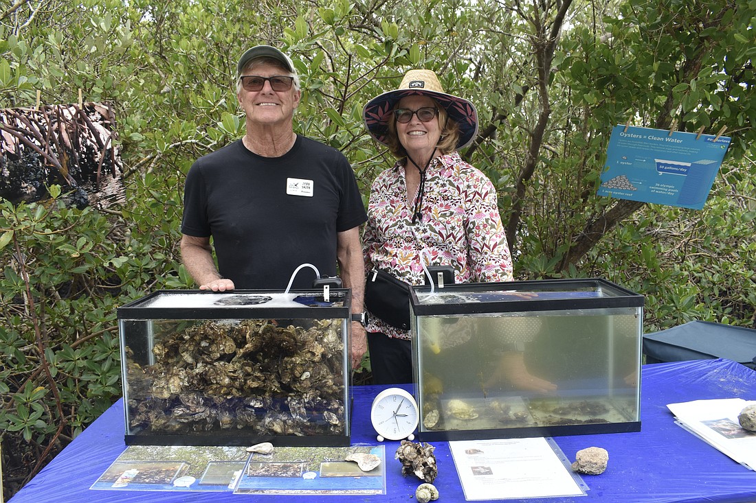 Jeff Smith, president of the Landings Management Association, and Judi Smith, display two tanks into which they dumped phytoplankton, one with oysters and one without, to show the work the oysters do in keeping the water clean.