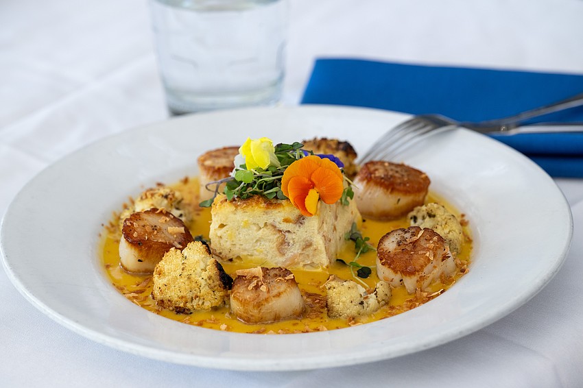 Seared sea scallops are presented on top of a golden sauce with roasted cauliflower and delicate garnishes, showcasing Harry’s Continental Kitchens’ blend of refined presentation and coastal flavor. Seared sea scallops are presented on top of a golden sauce with roasted cauliflower and delicate garnishes, showcasing Harry’s Continental Kitchens’ blend of refined presentation and coastal flavor.