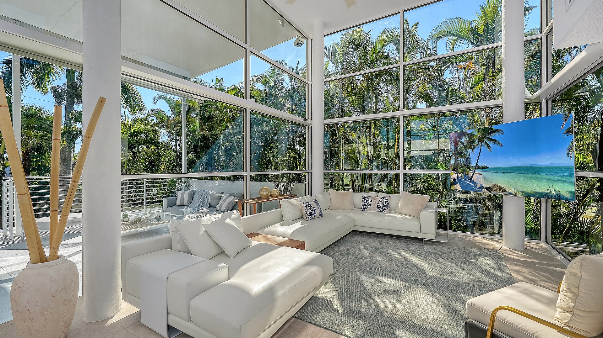 The spacious living area features 16-foot-high ceilings and views out to a forest of palm trees.