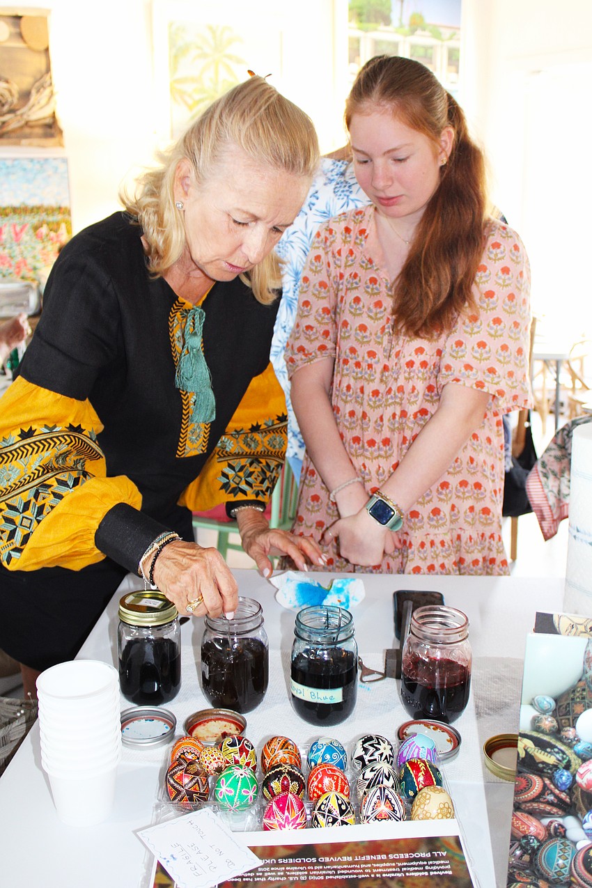 Pysanky artist Roksolana Tymiak-Lonchyna helps Bliss Rippy with dyeing her egg at the March 31 workshop at Driftwood Beach Home & Garden.