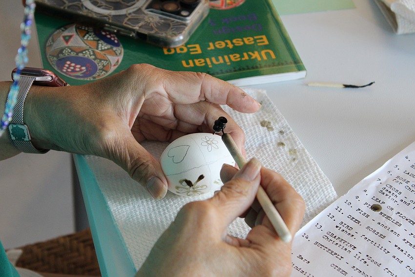 Lynda Pfeiffer lays out her first lines of beeswax for her pysanky design at a workshop on traditional Ukrainian egg dyeing.