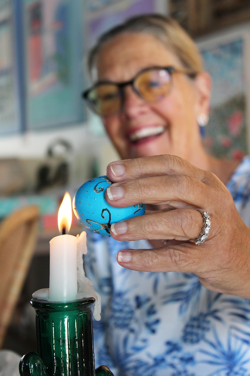 Pam Anderson melts the wax off her pysanky egg to unveil the final design.