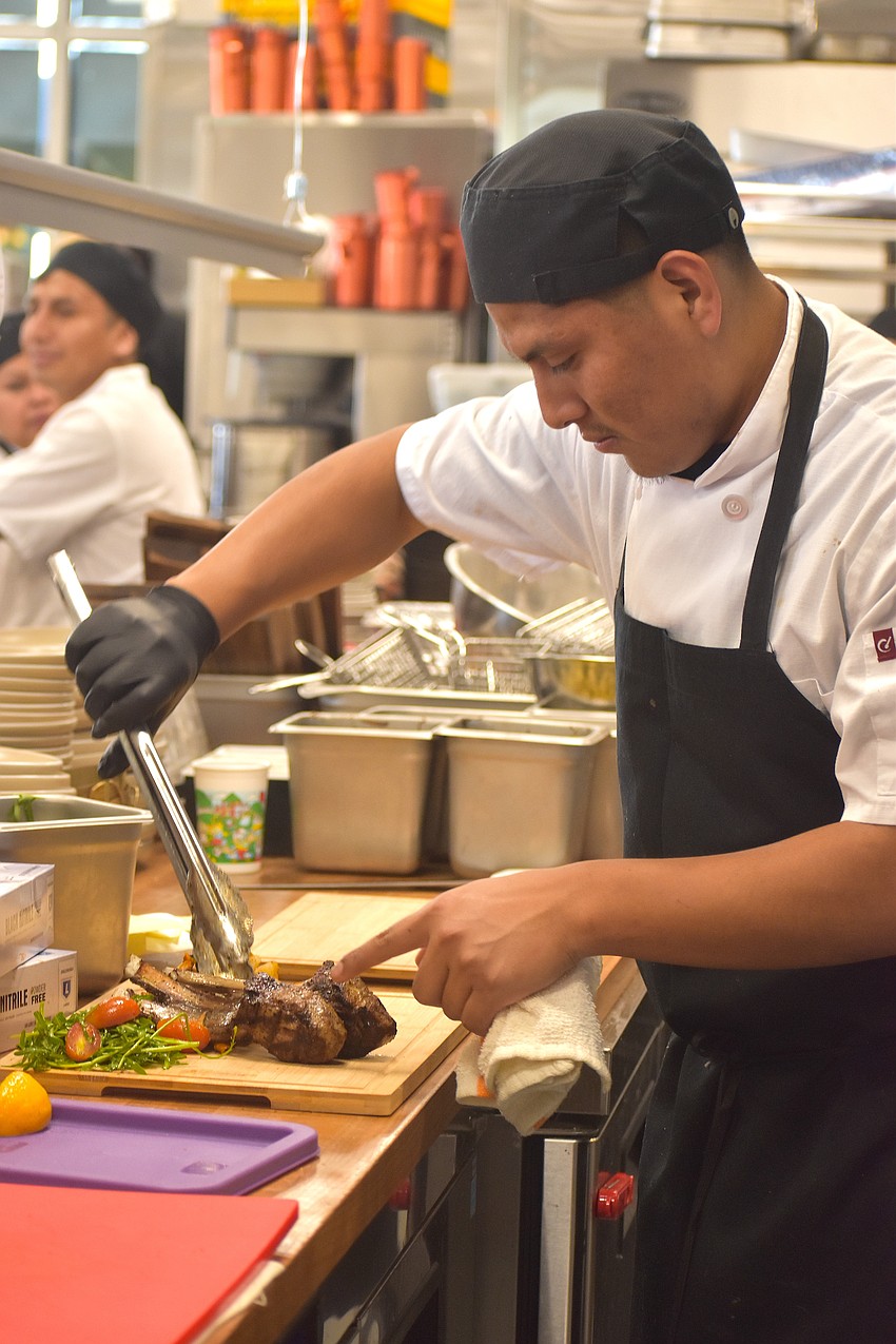 Victor Gomez, who has worked at Blu Kouzina for over 6 years, prepares lamb shanks at the new location at University Town Center.