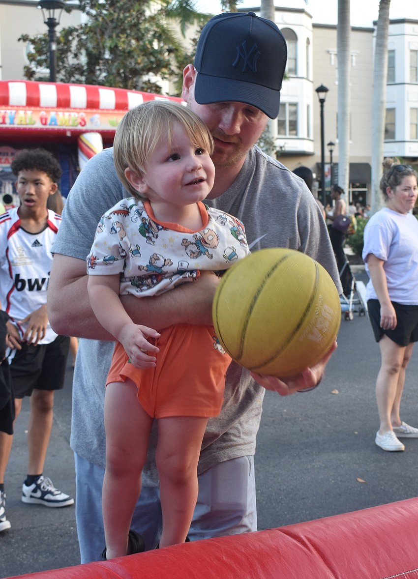 Lakewood Ranch's Elliott Crawford, 2, gets some assistance from Matt Crawford to make a basket at Music on Main April 3.