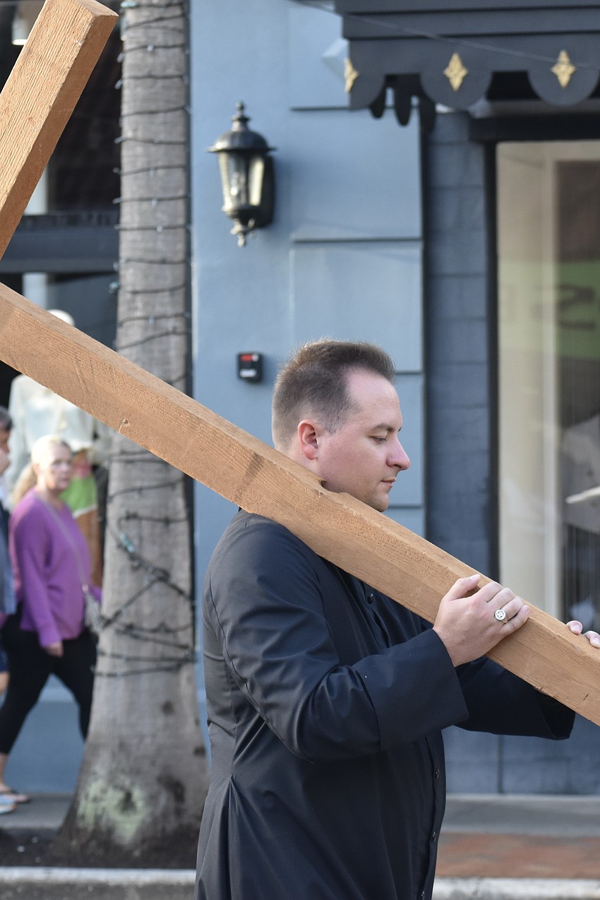 Rev. Mason Waldhauser, associate rector for adult formation at Church of the Redeemer, walks with the cross.