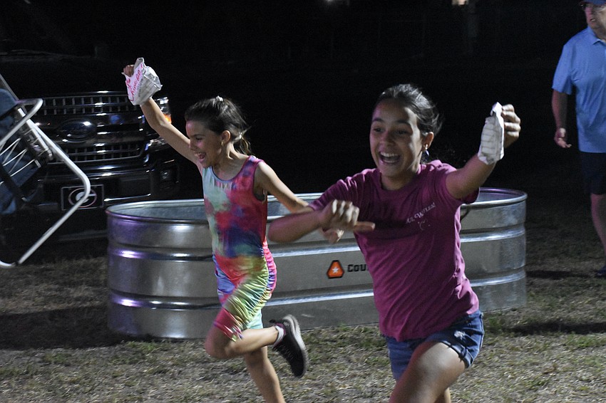 Marian Gil, 11, and Italia Dentici, 9, run with some bags of Chick-fil-A.