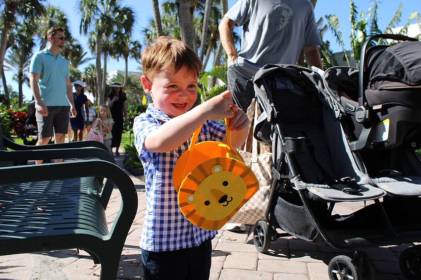 Two-year-old Davis Moore happily adds an Easter egg to his lion Easter basket.