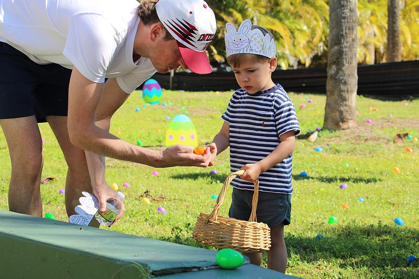 Brett Hopen shows Beau how to collect the Easter eggs in his basket.