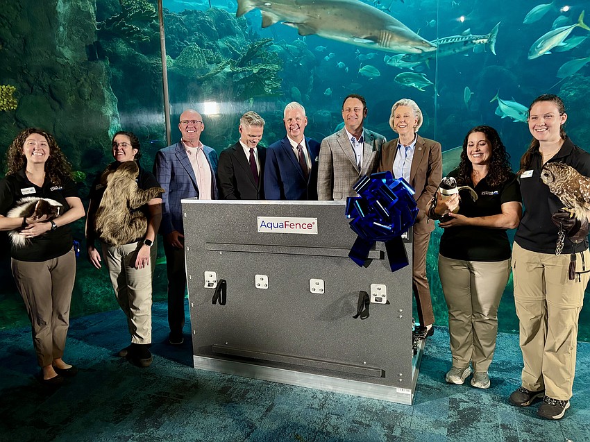 (From left to right) The Florida Aquarium CEO Roger Germann, AquaFence CEO Michael Juuhl, AquaFence CRO Patrik Hansson, Tampa General Hospital CEO John Couris and Tampa Mayor Jane Castor pose with animals and a portion of AquaFence flood barrier inside The Florida Aquarium.