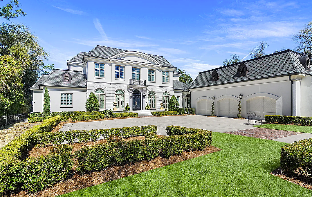 Riverfront two-story home features five bedrooms, five full and two half-bathrooms, a guest house, porches, an outdoor kitchen, a pool and a three-car garage.
