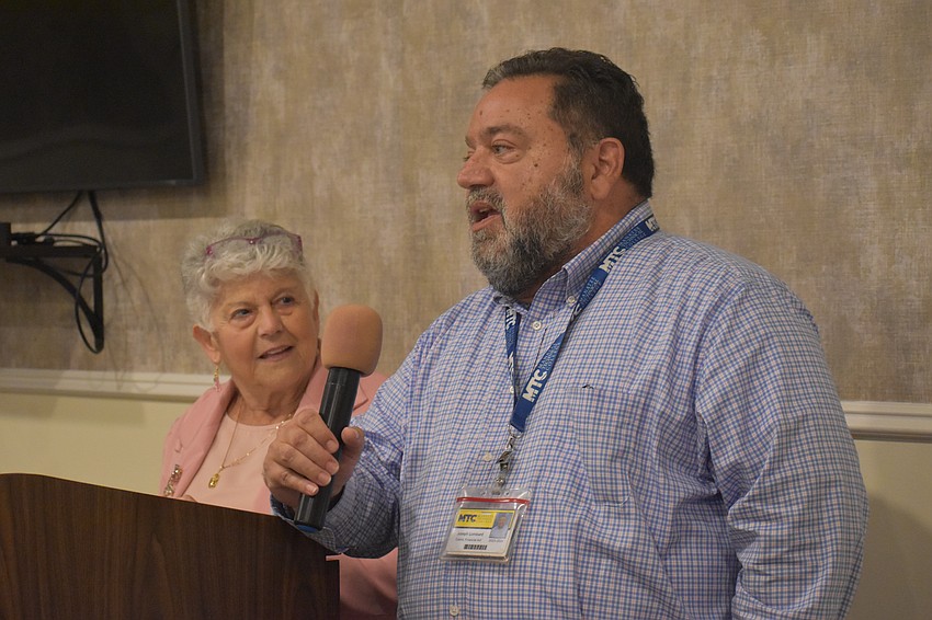 Scholarship Chair Carol McManus listens as Joseph Lombard, a financial aid coordinator at Manatee Technical College, accepts a scholarship on behalf of Elexis Richardson.