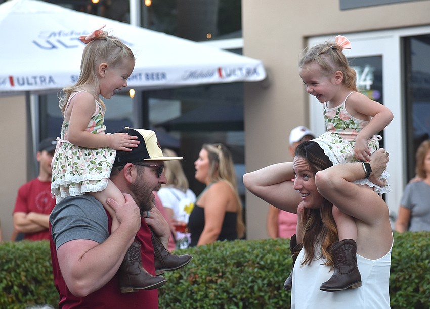 Twin sisters Adeline and Blakely take a ride on the shoulders of their parents, David and Chelsea Marvel, at the Lakewood Ranch Block Party April 10.