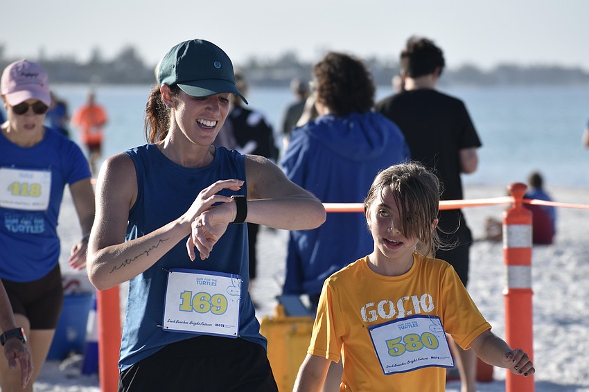 Gocio Elementary teacher Monica Fidura and third grader Charlotte Linderman approach the finish line with the Gocio Elementary School Runners Club.