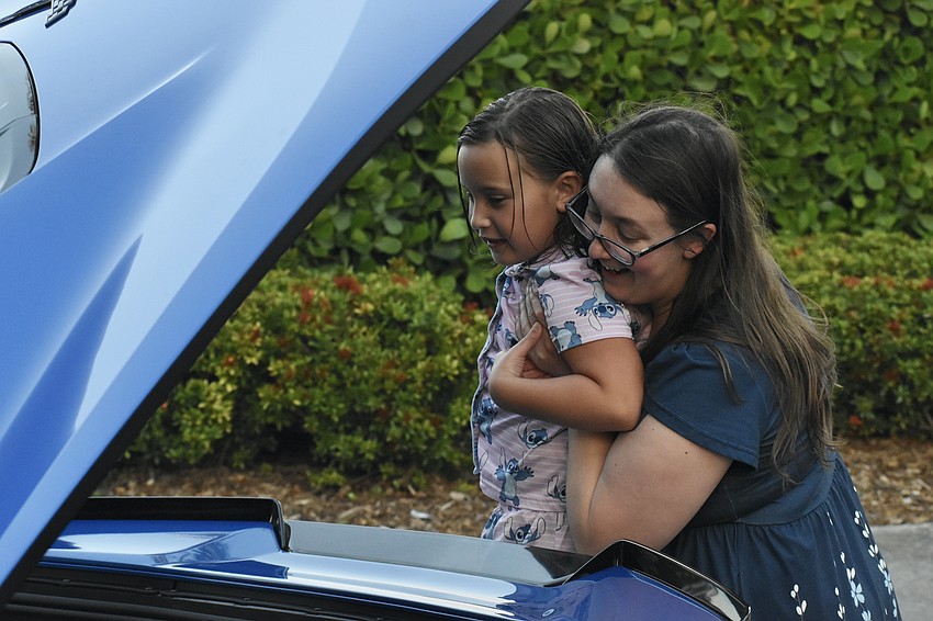 Athena DeChant, 7, gets a lift from her mother Leah DeChant, to look inside a car on display.