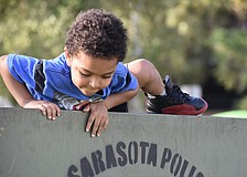 Za'Tajh Coach, 3, climbs over a barrier in the obstacle course.
