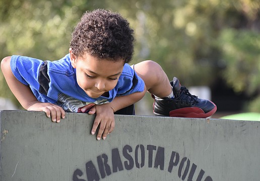 Za'Tajh Coach, 3, climbs over a barrier in the obstacle course.