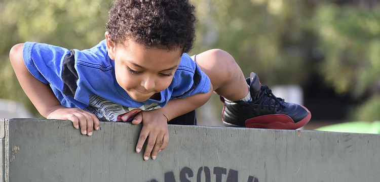 Za'Tajh Coach, 3, climbs over a barrier in the obstacle course.