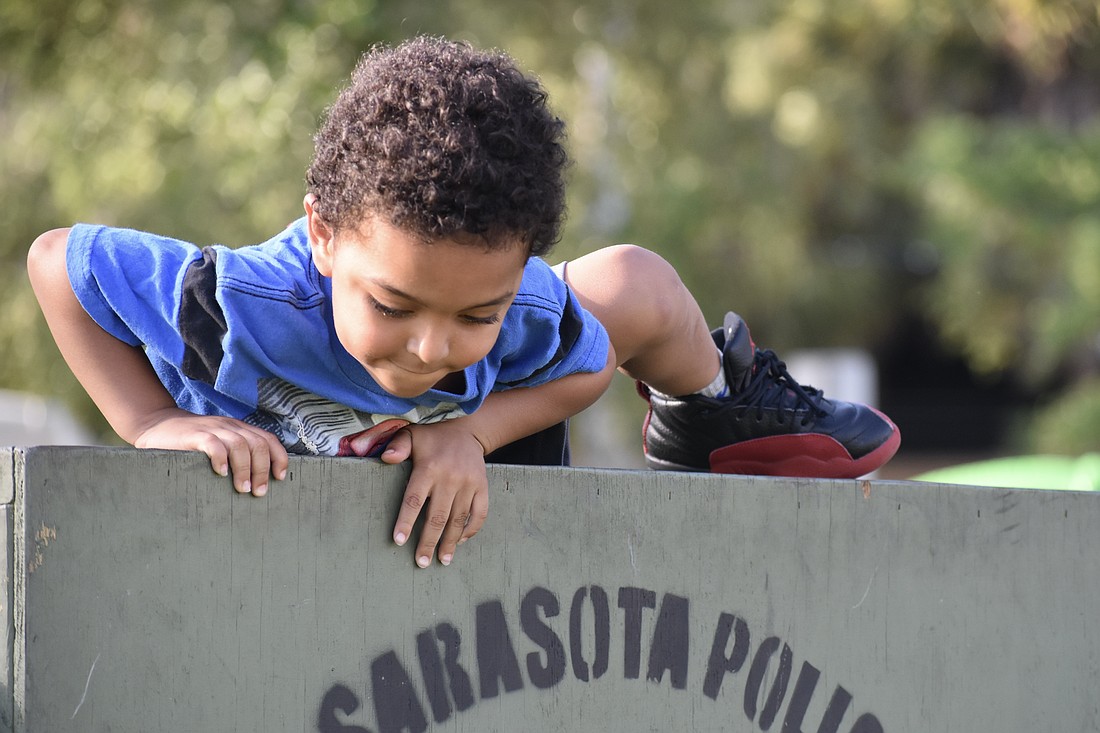 Za'Tajh Coach, 3, climbs over a barrier in the obstacle course.