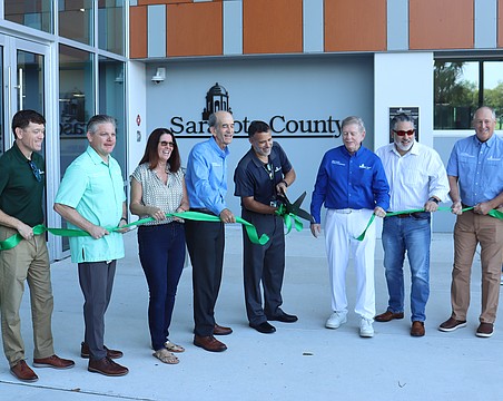 From left, Assistant County Administrator Brad Johnson, County Administrator Jonathan Lewis and County Commissioners Teresa Mast, Ron Cutsinger, Mark Smith, Joe Neunder and Tom Knight flank Matt Osterhoudt as he cuts the ribbon at the new development services one stop shop.