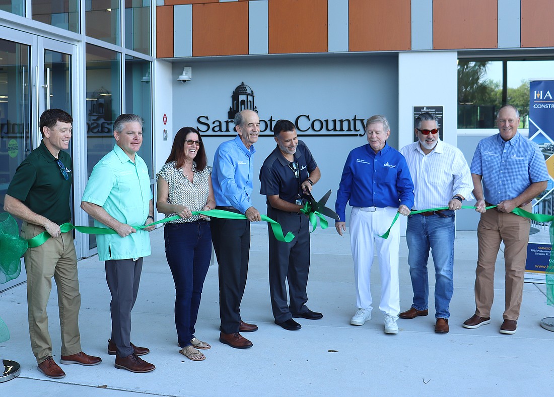 From left, Assistant County Administrator Brad Johnson, County Administrator Jonathan Lewis and County Commissioners Teresa Mast, Ron Cutsinger, Mark Smith, Joe Neunder and Tom Knight flank Matt Osterhoudt as he cuts the ribbon at the new development services one stop shop.