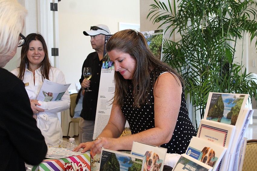 Kim Verreault, president and CEO of the Longboat Key Chamber of Commerce, checks a completed passport at the Meet Greet Eat social. Attendees at the free event got to nosh, chat and enter raffle drawings.