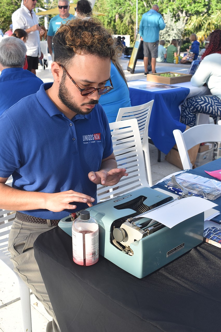 Andres Bonett of UnidosNow types a poem for a donor on a typewriter he brought along.