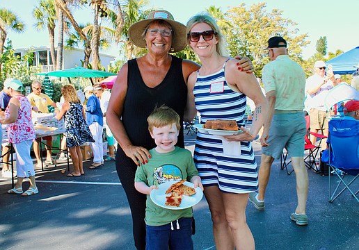 Margarita Lenk, Ari and Stephanie Weiner pick out their slices at the Longboat Harbour annual farewell pizza party on April 16.