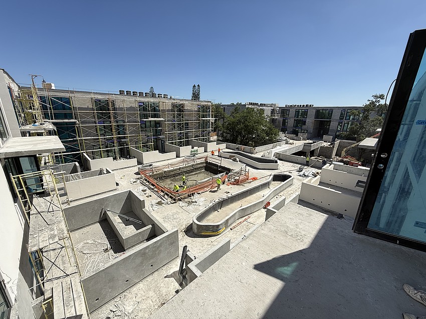 The residents' pool and outdoor amenity area at Bath + Racquet Residences & Club is positioned in a courtyard surrounded by condo buildings.