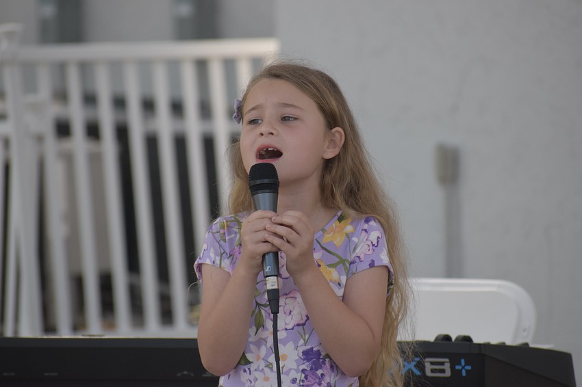 Music Compound student Gianna Krick, 8, sings for attendees.