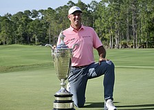 Stewart Cink kneels by the Alfred S. Bourne Trophy. His name will be the 86th engraved into the silver prize of the Senior PGA Championship — the oldest major on the PGA Tour Champions.