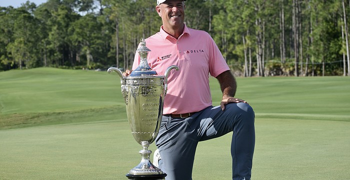 Stewart Cink kneels by the Alfred S. Bourne Trophy. His name will be the 86th engraved into the silver prize of the Senior PGA Championship — the oldest major on the PGA Tour Champions.