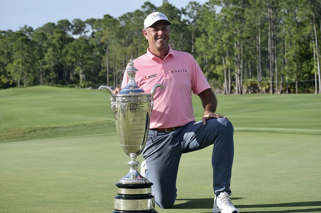 Stewart Cink kneels by the Alfred S. Bourne Trophy. His name will be the 86th engraved into the silver prize of the Senior PGA Championship — the oldest major on the PGA Tour Champions.