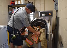 Lieutenant Jack Gamble loads a set of bunker gear into the Speed Queen Extractor at Station 1 in Lakewood Ranch.