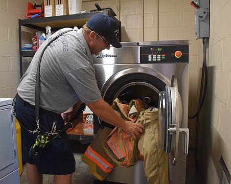 Lieutenant Jack Gamble loads a set of bunker gear into the Speed Queen Extractor at Station 1 in Lakewood Ranch.