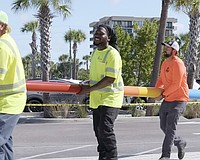Workers carry one of two storm surge poles Sarasota County has installed at Siesta Beach and Manasota Beach.