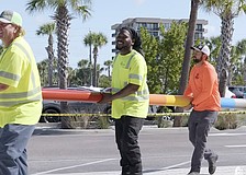 Workers carry one of two storm surge poles Sarasota County has installed at Siesta Beach and Manasota Beach.